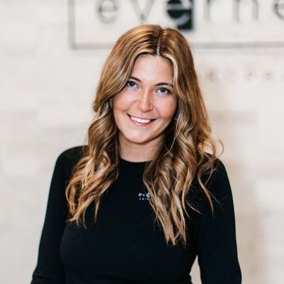 Chiropractic Chanhassen MN Olivia Front desk staff member, Olivia, smiling for photo wearing black top.